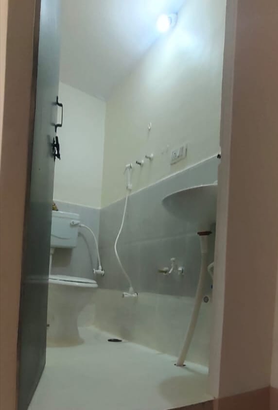 Clean and hygienic attached washroom in the Boys PG in Hubli, showing the sink, modern toilet, and bright lighting.