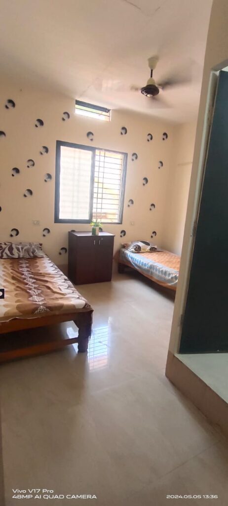 Clean, twin-sharing PG room in Hubli with natural light and simple beds, suitable for students or working professionals.